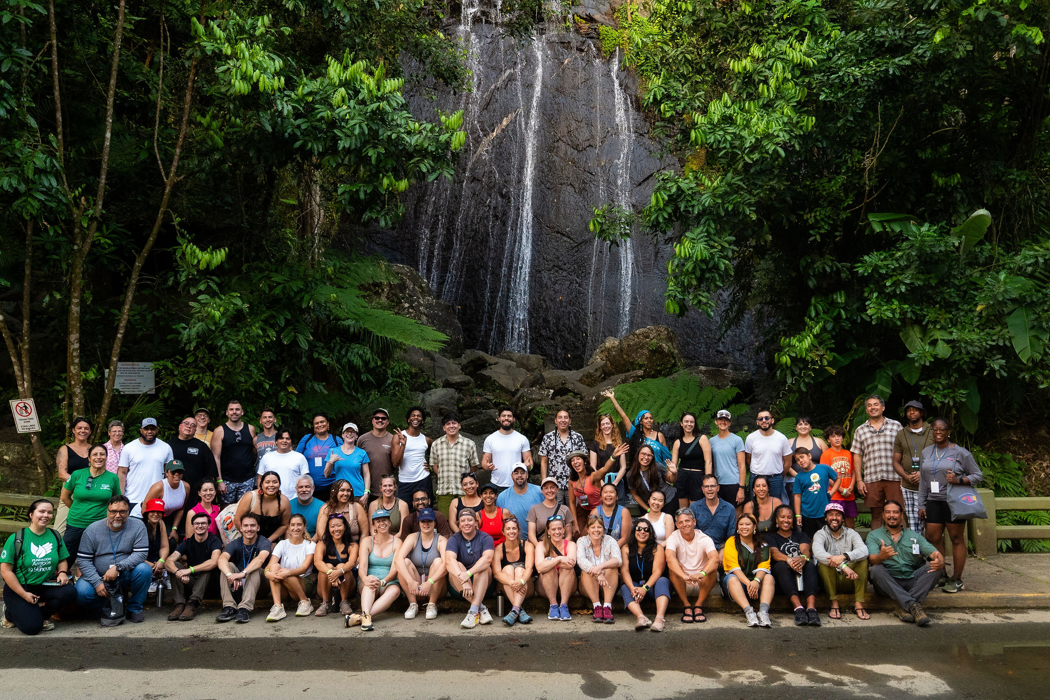 Large group gathered under a waterfall